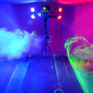 Eine Lichtanlage taucht den Raum in rotes, grünes und blaues Licht. Im Nebel erkennt man farbige Strahlen und Laserprojektionen.